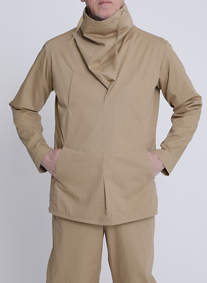 Schlupfblouson mit angeschnittenem Kaminkragen und 2 großen Bauch- und 1 Brusttasche. Sickel Pants mit angeschnittenem Bund und nach außen gewölbter Beinweite. Beides aus einem bahamabeigefarbenem Gabardine, 100 % Baumwolle.